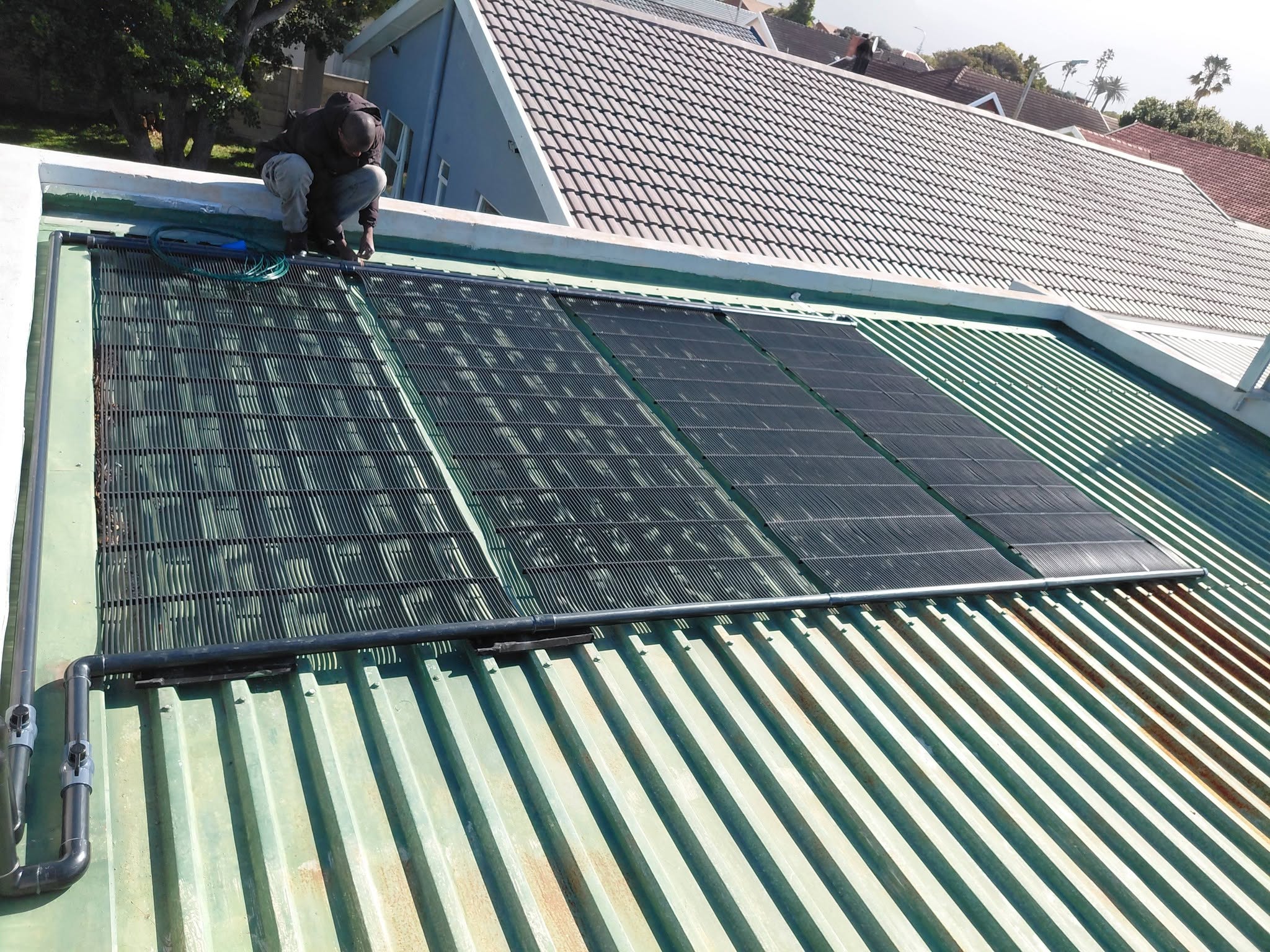 GridFree installer fitting solar collectors on a roof